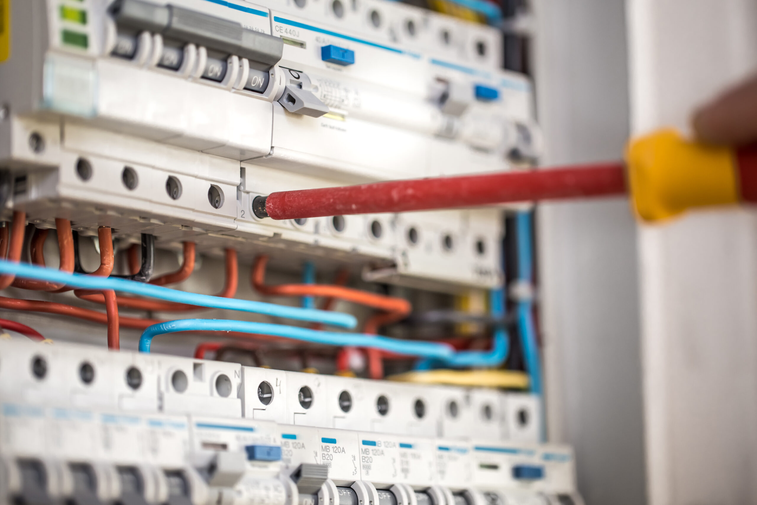 Man electrical technician working switchboard with fuses installation connection electrical equipment close up scaled
